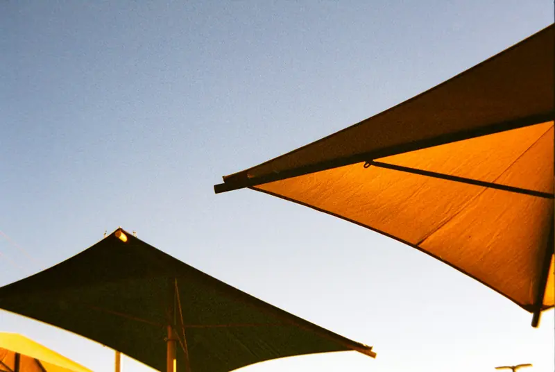 Two large fabric shade umbrella structures against a clear sky