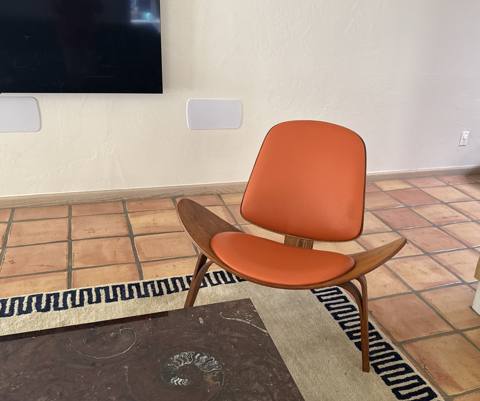After: orange leather three-leg shell chair, front view